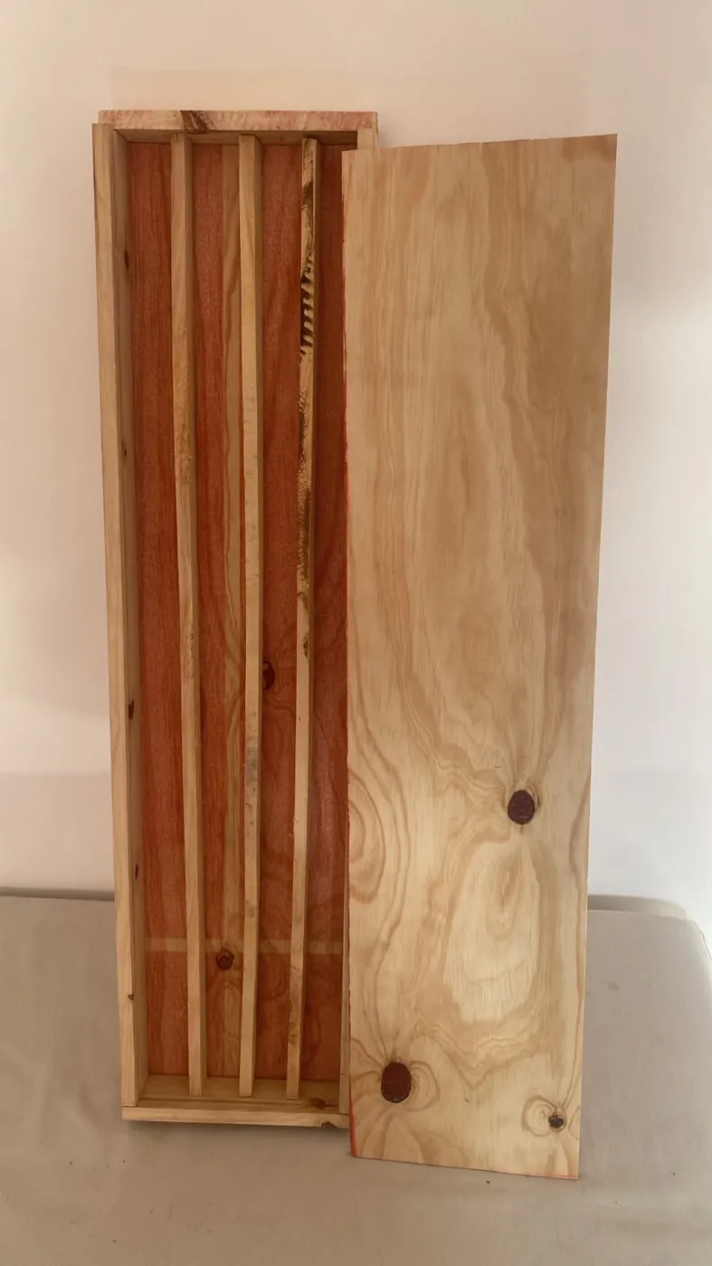 Caja GEOBOX abierta: canales con separadores de madera e interior tratado, con la tapa corrediza apoyada al lado